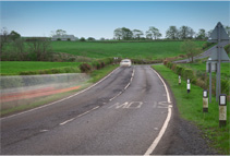 Image of a curved road with slow road markings in the countryside Ireland